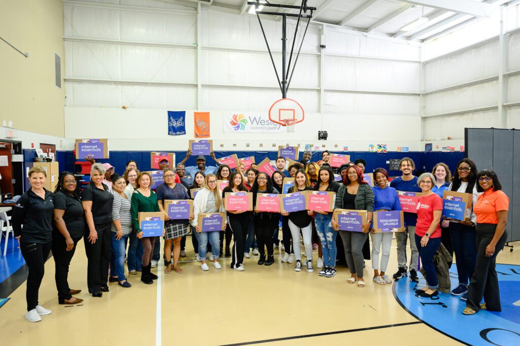 A group of people smile with new laptops during Digital Inclusion Week.