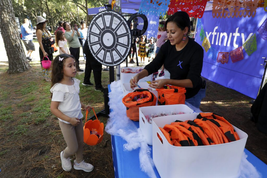 Attendees and kids get free hand outs at the Xfinity tent during the Comcast Kingwood Takeover, held at the Kingwood Town Center Park on Saturday, Oct. 28, 2023 in Kingwood, TX. (Michael Wyke/AP Images for Comcast)