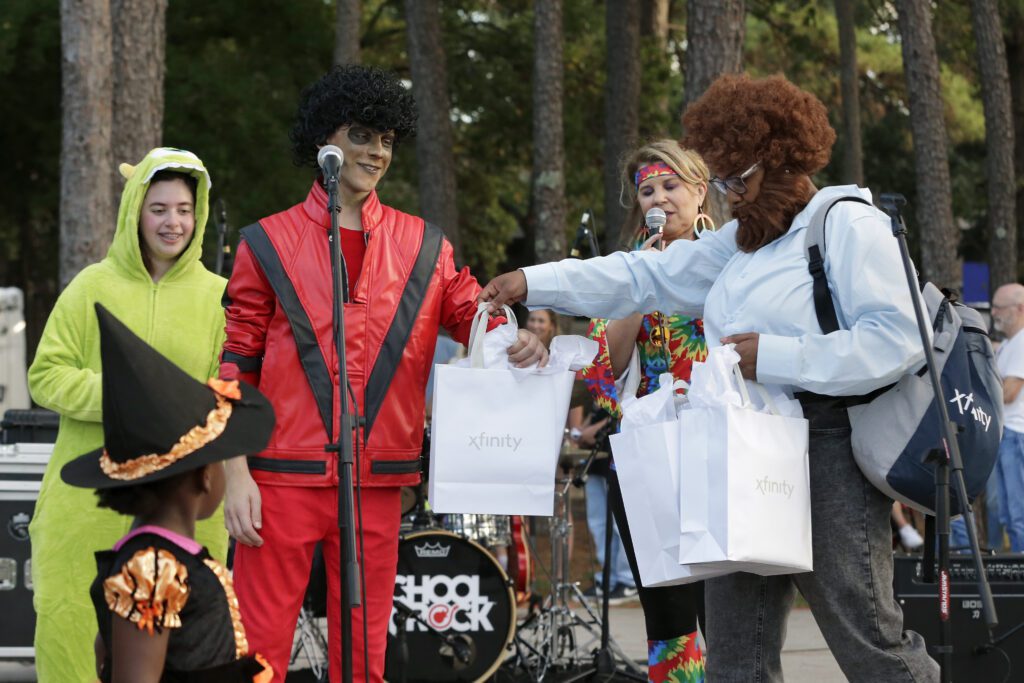 Comcast staff officiate a costume contest on the stage during the Comcast Kingwood Takeover, held at the Kingwood Town Center Park on Saturday, Oct. 28, 2023 in Kingwood, TX. (Michael Wyke/AP Images for Comcast)