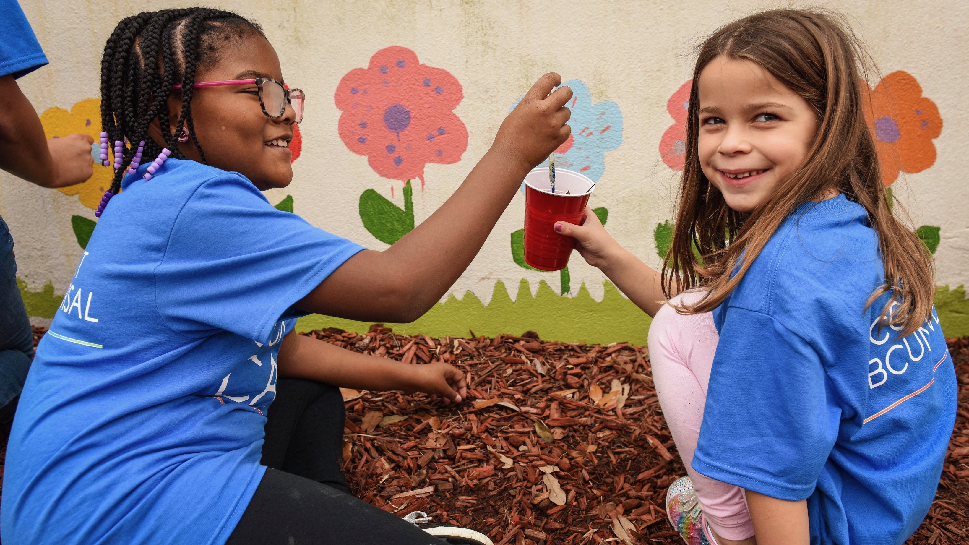 Two young Comcast Cares Day volunteers paint a mural.