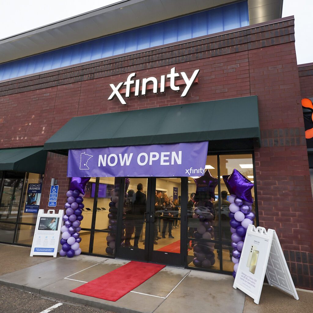 Storefront of Xfinity store with "Now Open" purple banner and purple balloon towers.