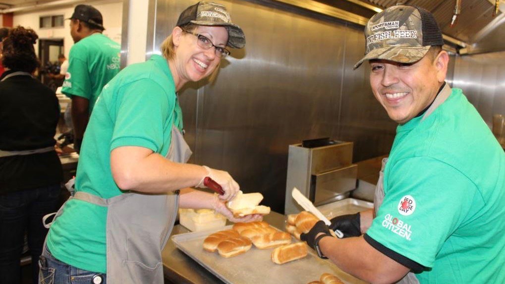 Two Comcast Cares Day volunteers prepare food.