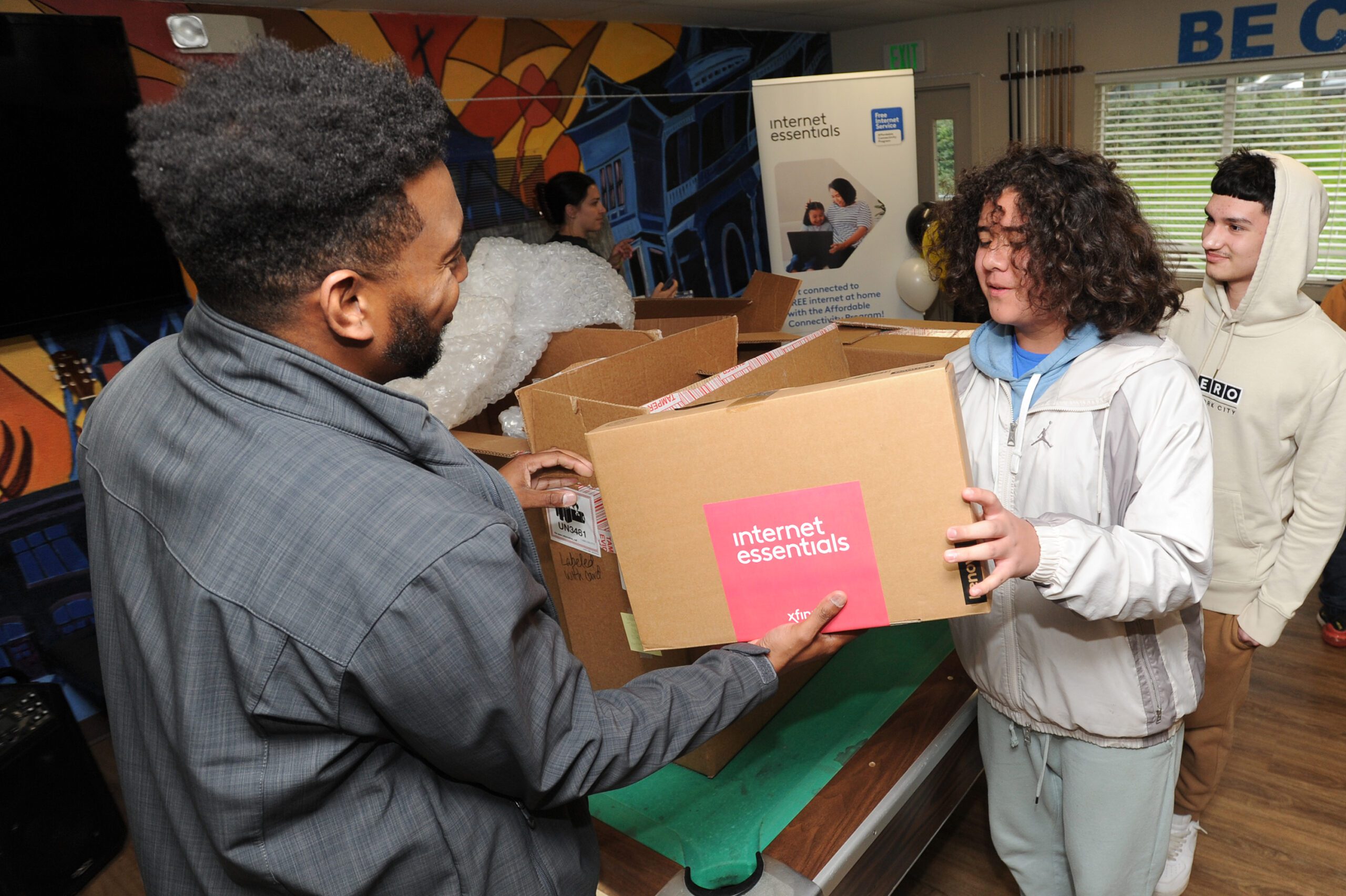 A youth receives a laptop from a Comcast employee.