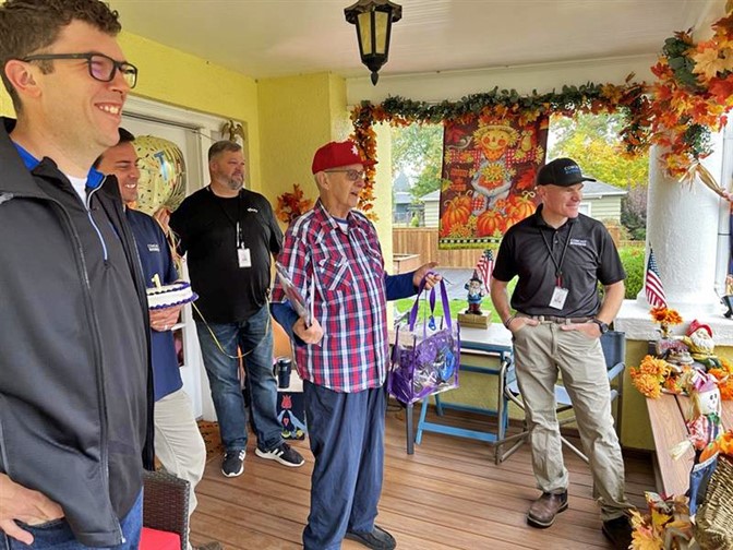 Jerry Lauzon stands on his porch with Comcast employees. 
