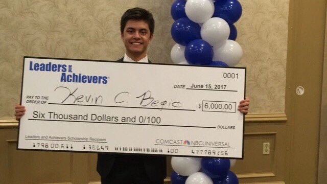 Kevin Begic holds and oversized check presented to him by the Leaders and Achievers Program.