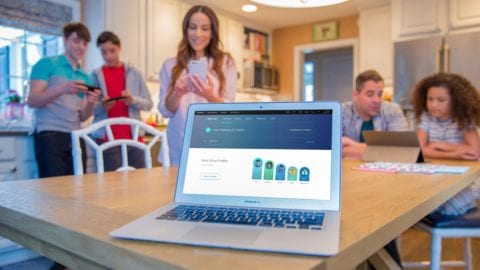 A family is gathered around a laptop displaying the status of their Xfinity xFi devices.