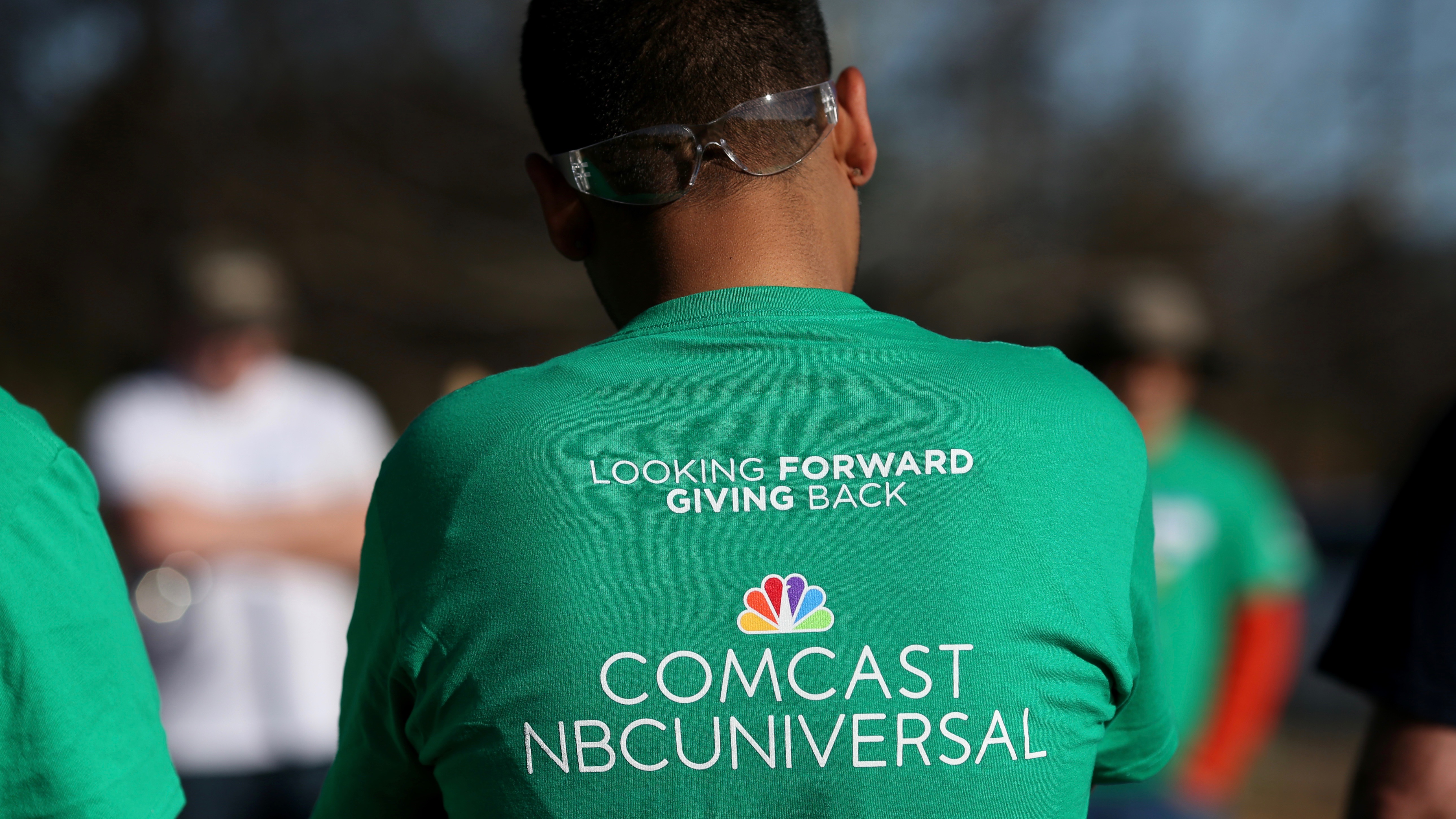 A Comcast Cares Day volunteer wears a shirt that reads "Looking forward to giving back, Comcast NBCUniversal".