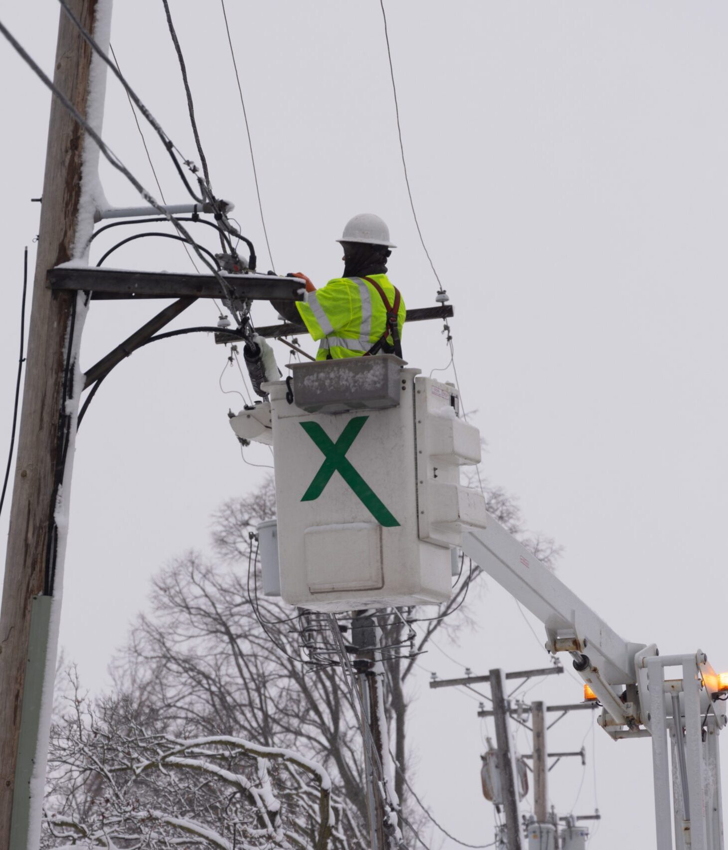 Response team Xfinity technician in a bucket truck works to repair the network during winter storm to return connectivity to customers.