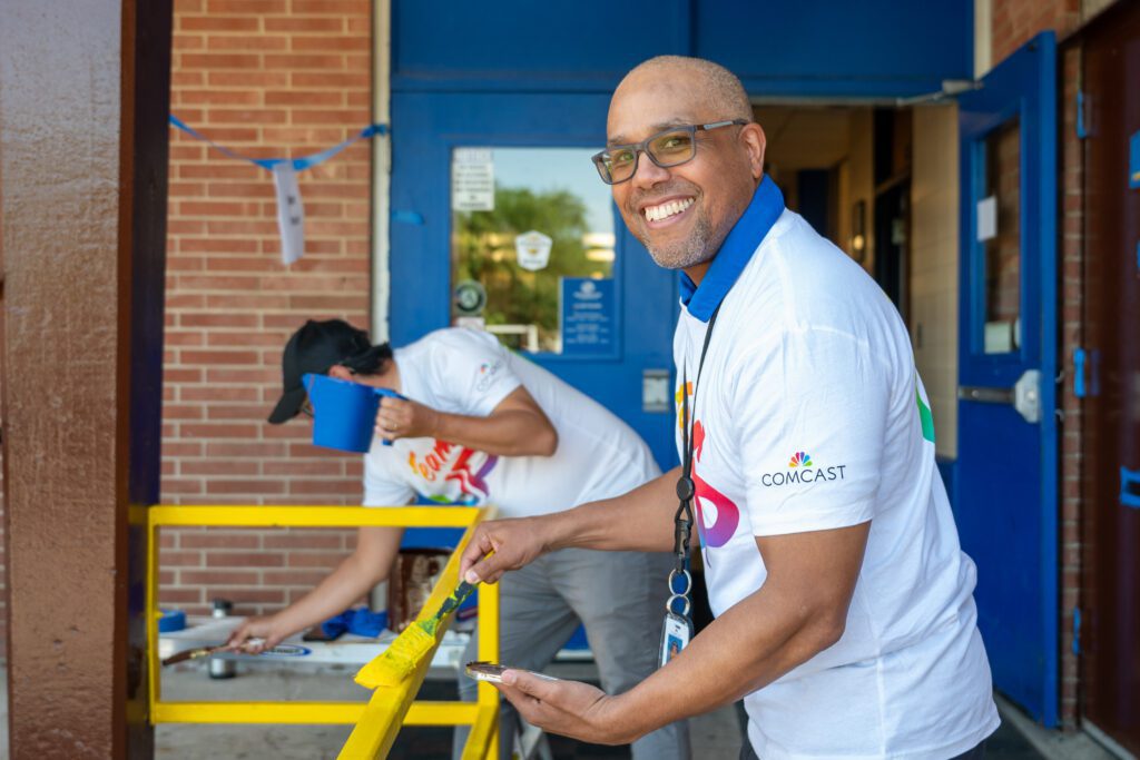 A Comcast TeamUp volunteer paints outdoor trim in the Boys & Girls Club of Flint's Averill Club site. 