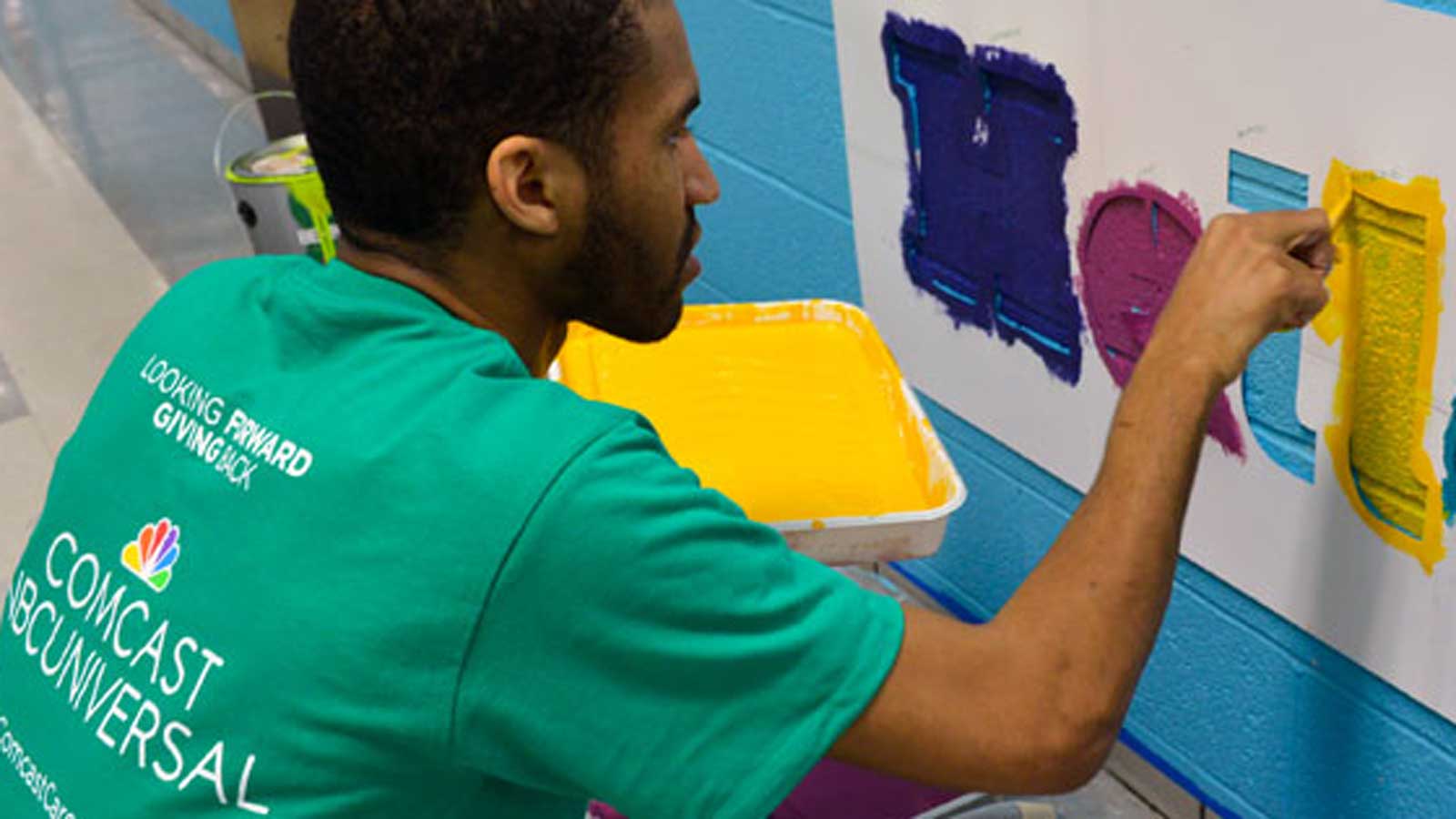 Comcast Cares Day volunteer painting mural