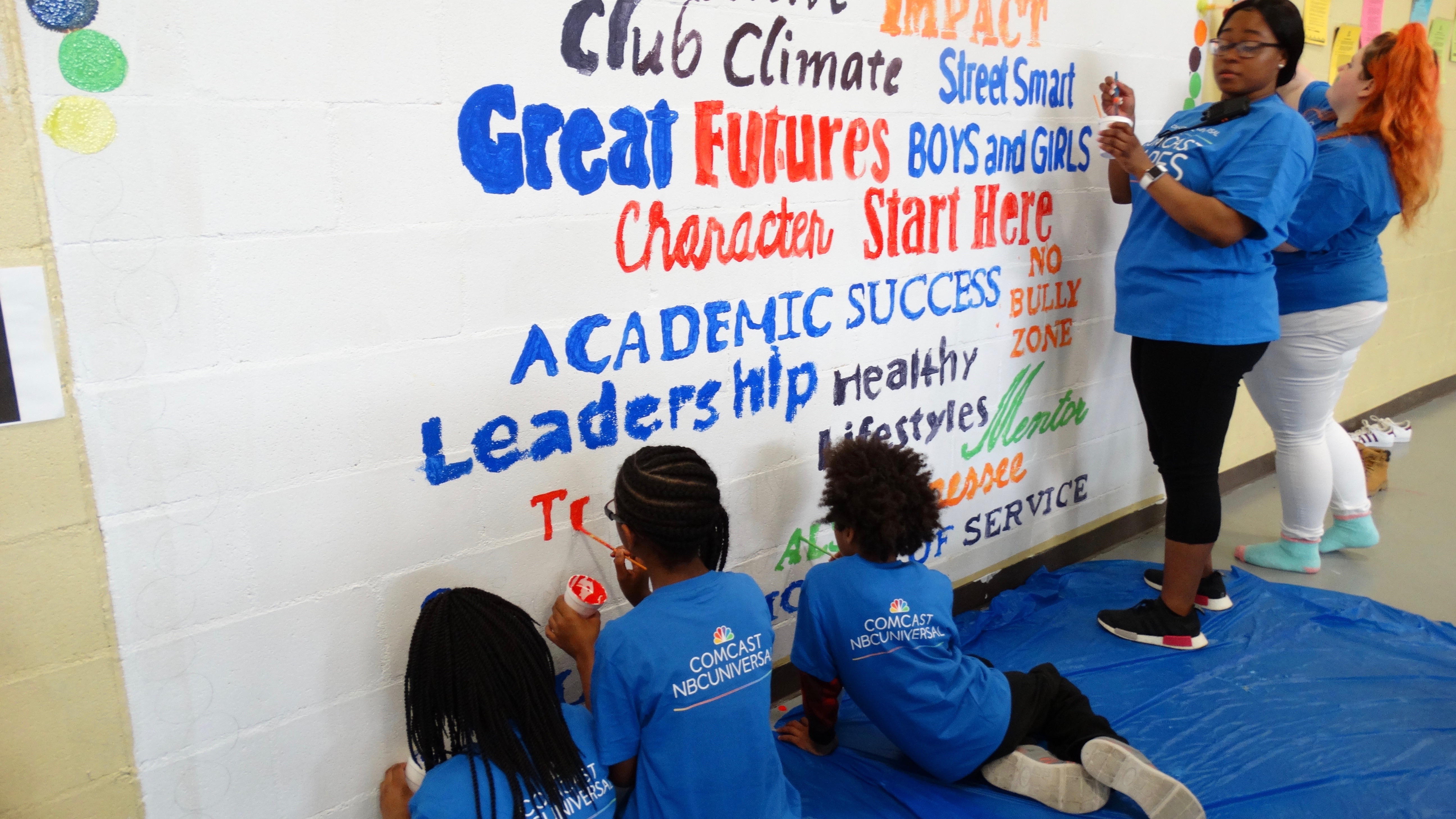 Young Comcast Cares Day volunteers paint a mural.