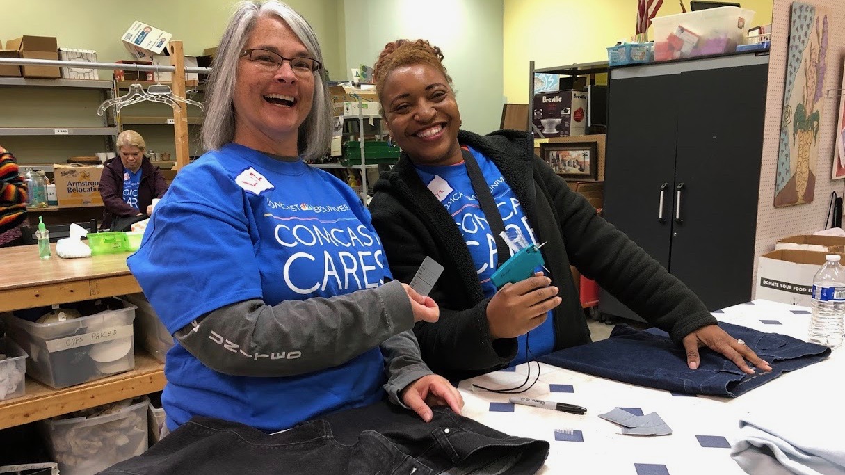 Two Comcast Cares Day volunteers sort clothing donations.