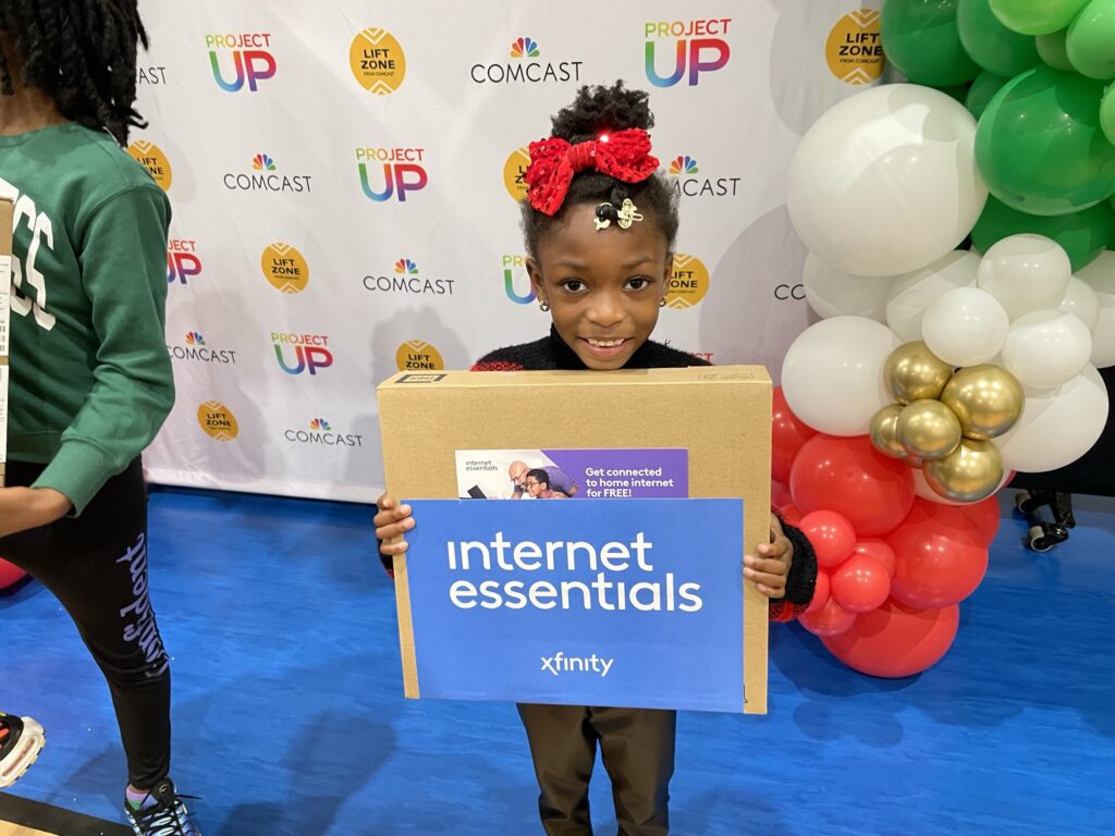 Young student at KIPP Ways holds up her new laptop from a recent Comcast donation.