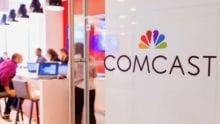 The Comcast logo on a glass door.