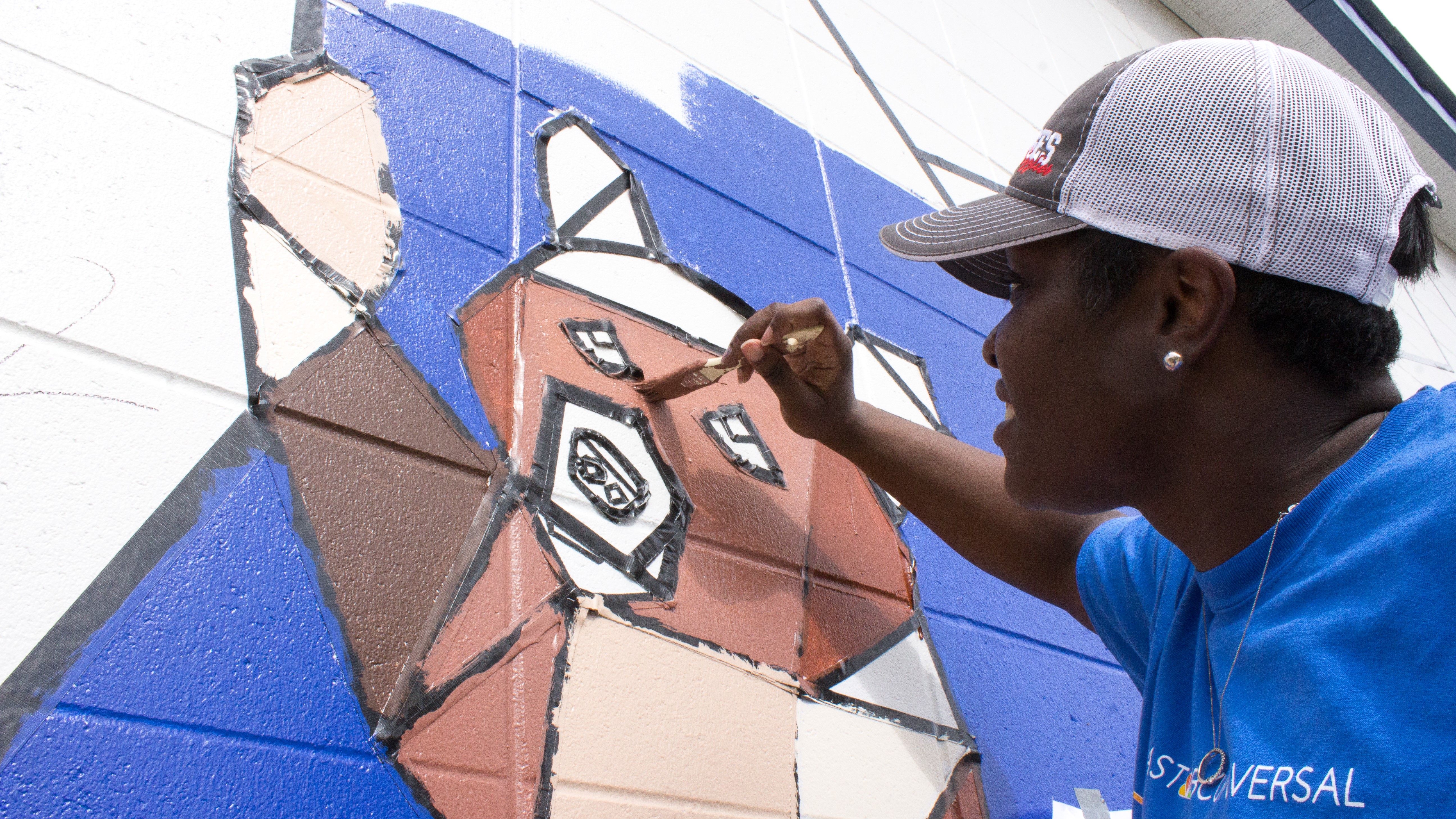 A Comcast Cares Day volunteer paints a mural.