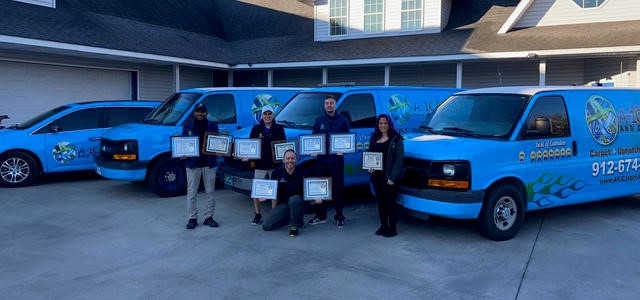 Staff stand in front of vans holding awards.