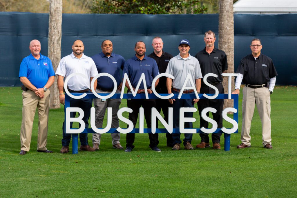 A group of Comcast Business employees standing behind a Comcast Business sign