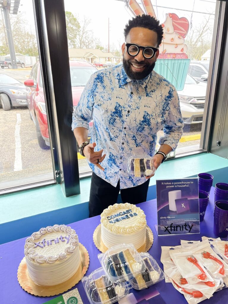 Jolando standing with Xfinity and Comcast Business themed cakes.