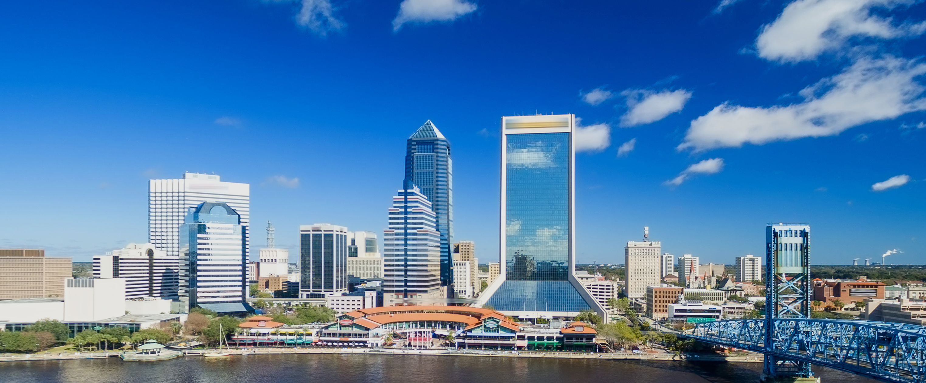 Buildings stand tall next to bright blue skies along the river in Jacksonville, Floirda.