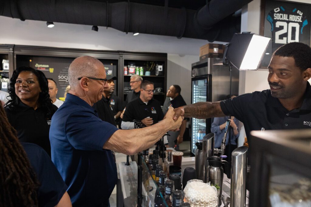 Chef Robert Irvine shaking hands with Social House Coffee owner Arrelious Benn.