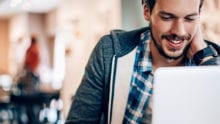 Man smiling while looking at a laptop screen