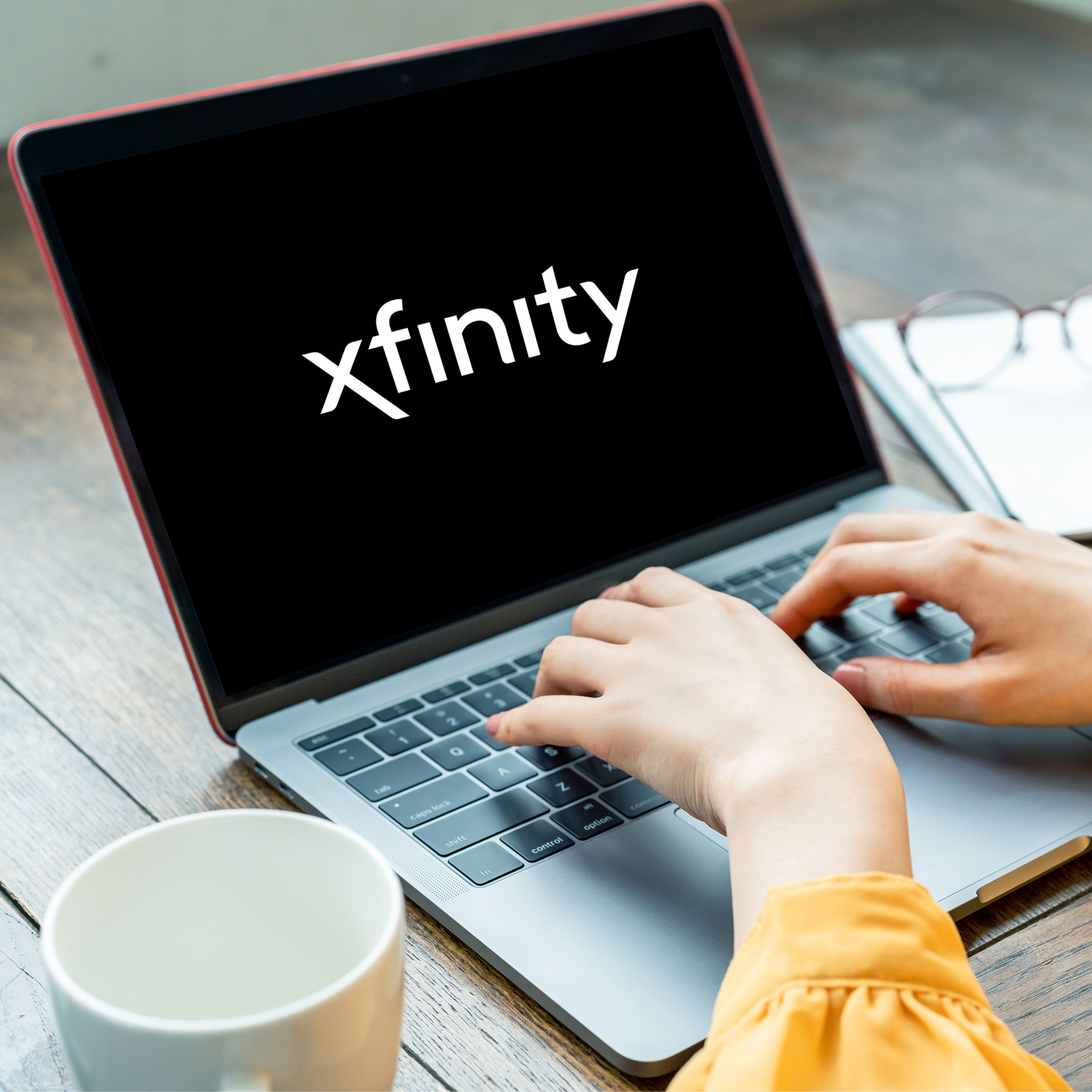 Person typing on laptop with Xfinity logo on screen