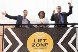 Three Comcast employees on top of Lift Zone banner