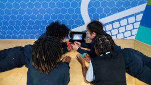 Four students laying on floor over gaming device