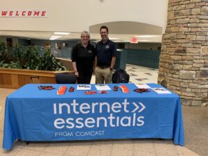 Woman and man standing at table with Internet Essentials banner