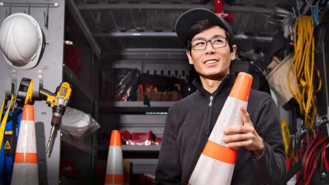 Technician holding orange cone outside his truck