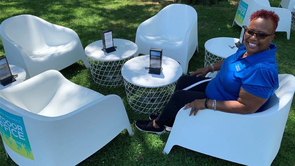 A Comcast Business technician sits in a chair on a lawn.