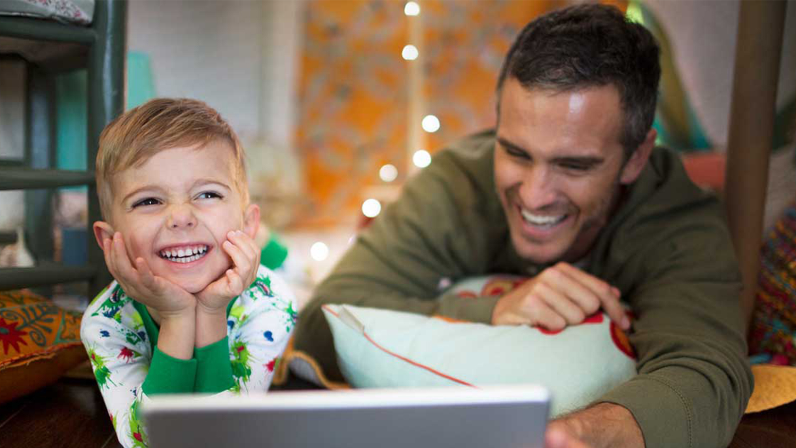 Father and son smiling looking at their laptop device.