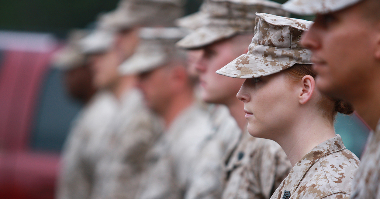 Members of the armed forces stand next to each other in a line.