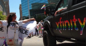 Participants in a Pride parade walk down a street.