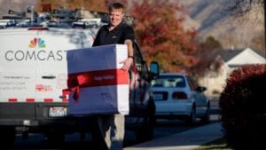 An Xfinity employee carries a large gift box.