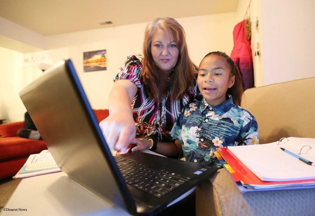 A woman pointing at a laptop screen for a young girl