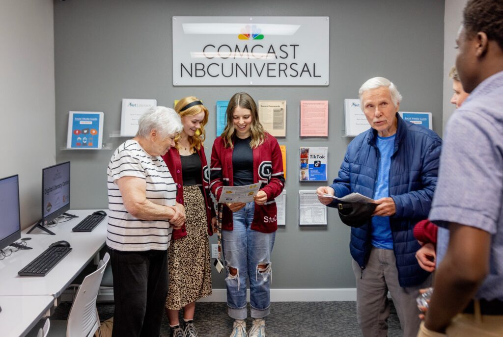 Students Tess Sellick, middle, and Carly Andrews, right, talk with Sandra Ring, left, in the new Comcast Digital Literacy Center at the Eagle Mountain Chamber of Commerce during a ribbon cutting event on Thurs., April 25, 2024 in Eagle Mountain, Utah.