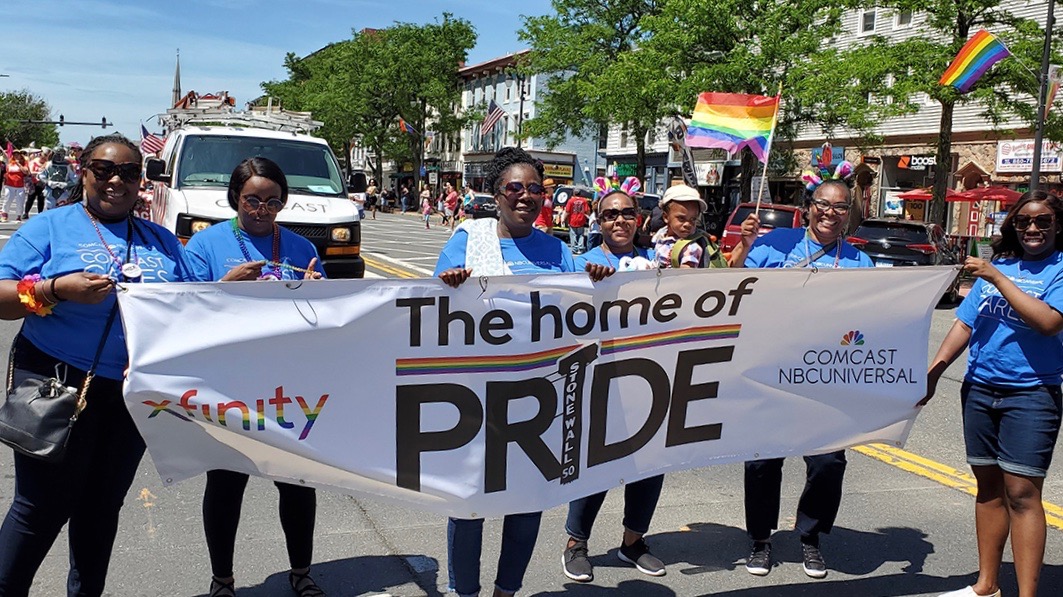 Pride parade with a banner being held by a few people