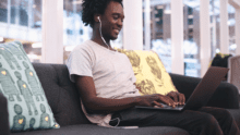 A person sits on a couch as they use a laptop.