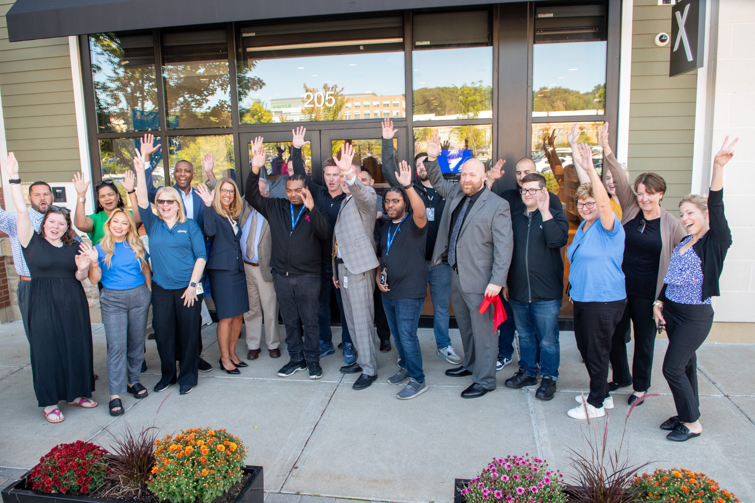 Large group of people waving and posing for picture at Grand Opening of the new Xfinity store in Westwood, MA.