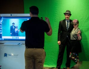 people dressed in 1950s outfits getting photo taken in front of green screen