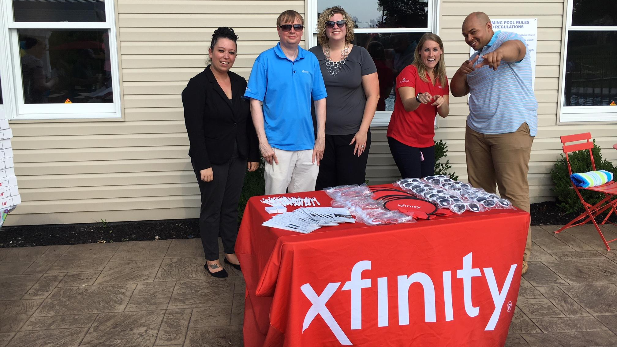 group of people posing by a comcast table