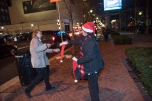 woman handing out Santa hat at Light Up Night