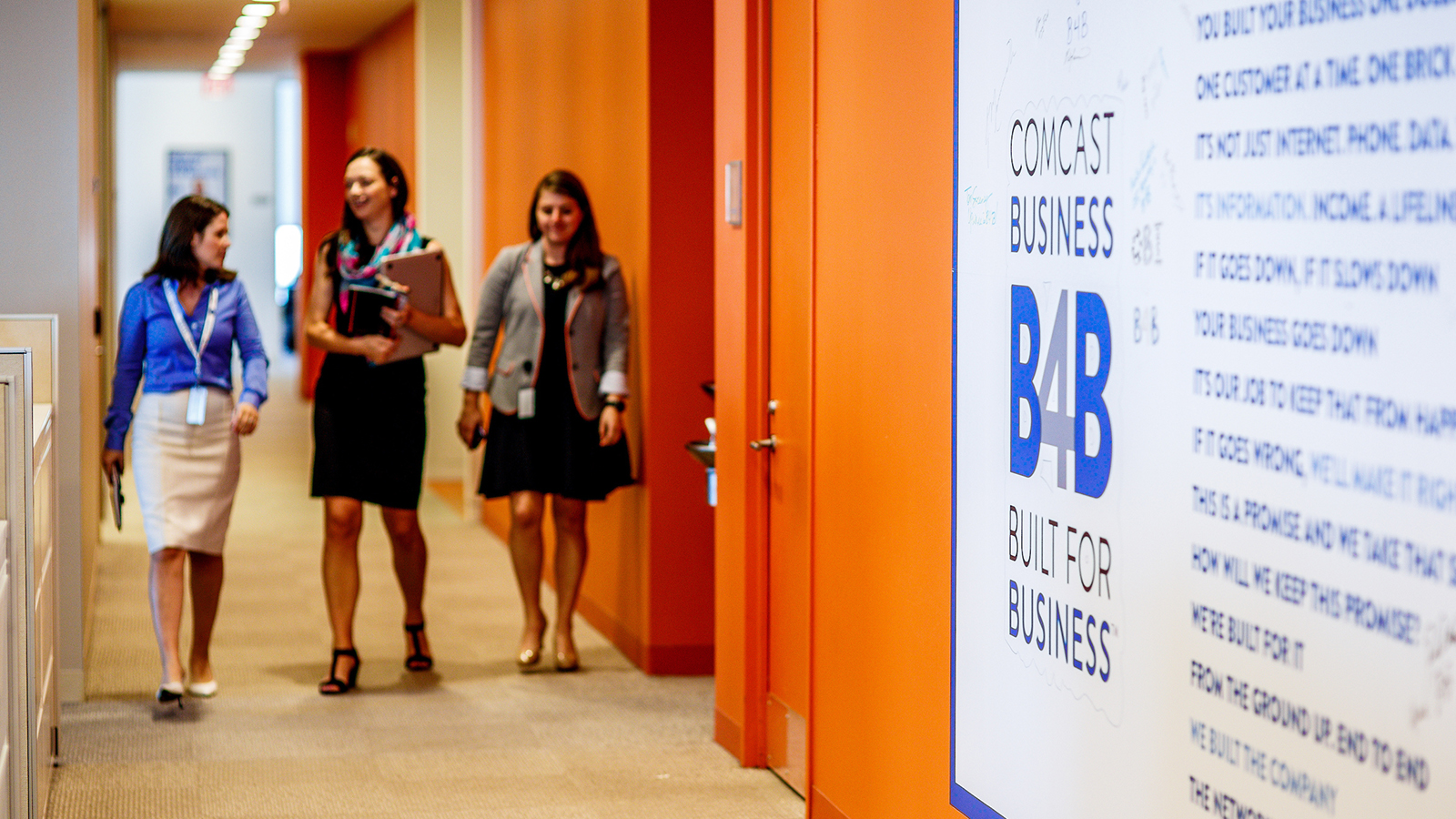 Women walking down a hallway past a Comcast Business logo
