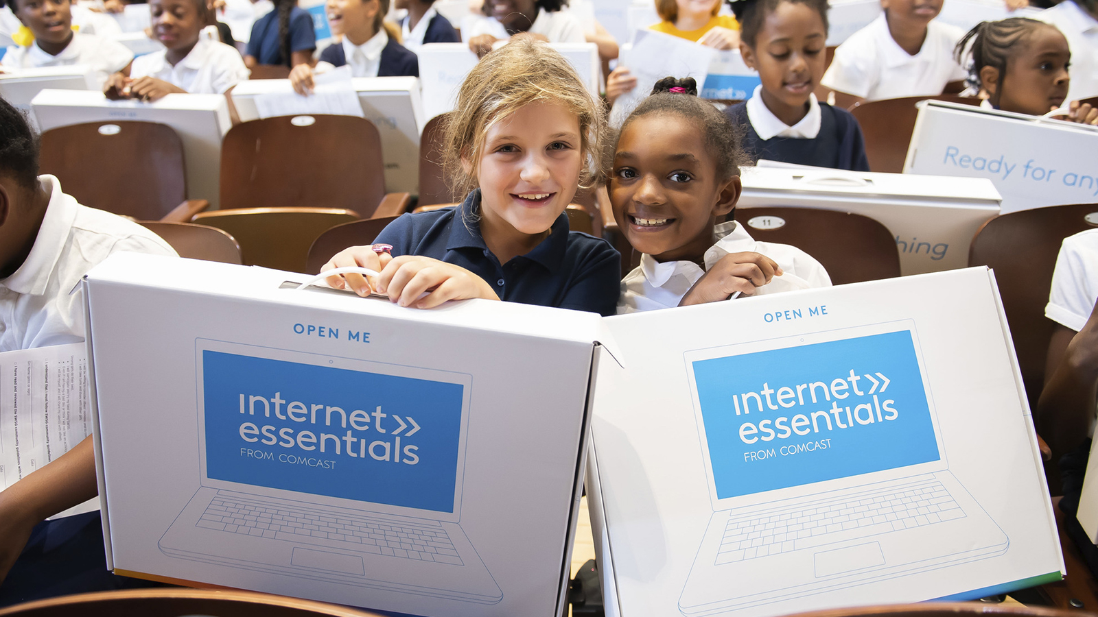 two girls holding Internet Essentials laptops at Comcast event