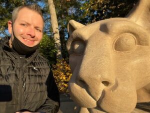 man standing next to Nittany Lion