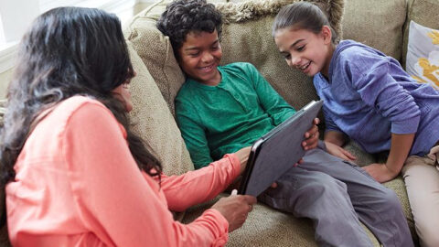 Mom and two children on couch, looking at tablet