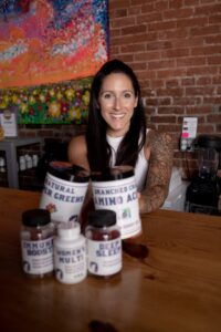Smiling woman with health supplements sitting on table in front of her