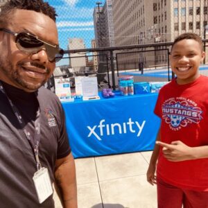 Man and boy standing in front of Xfinity logo