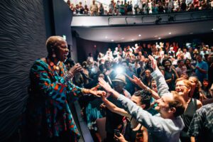 Person singing on stage with crowd cheering